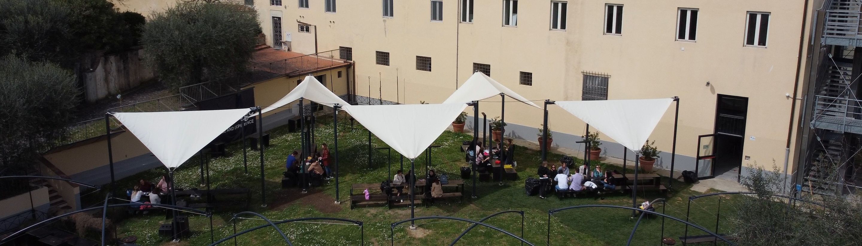 Students attending an open-air class under the tents in the campus garden