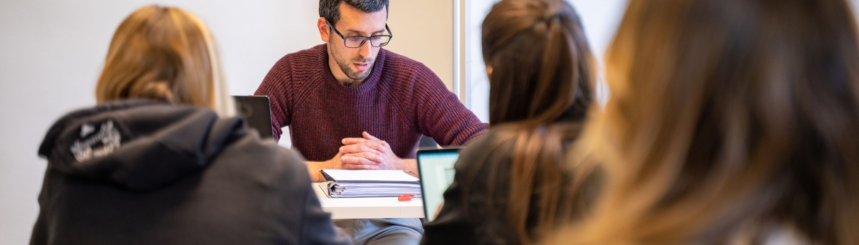 A professor working with students around a table at Unicollege