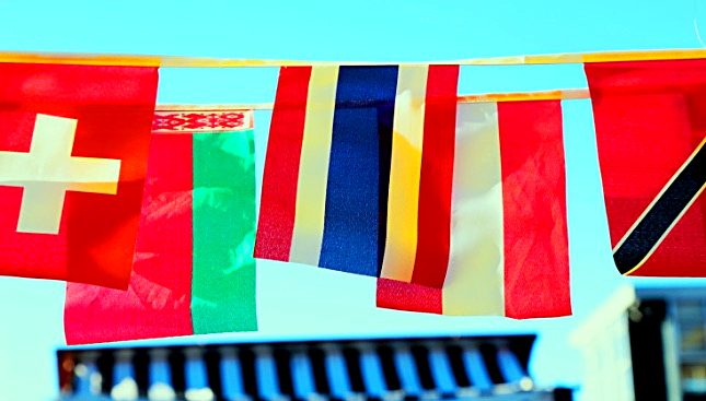 Flags of European countries strung against a blue sky