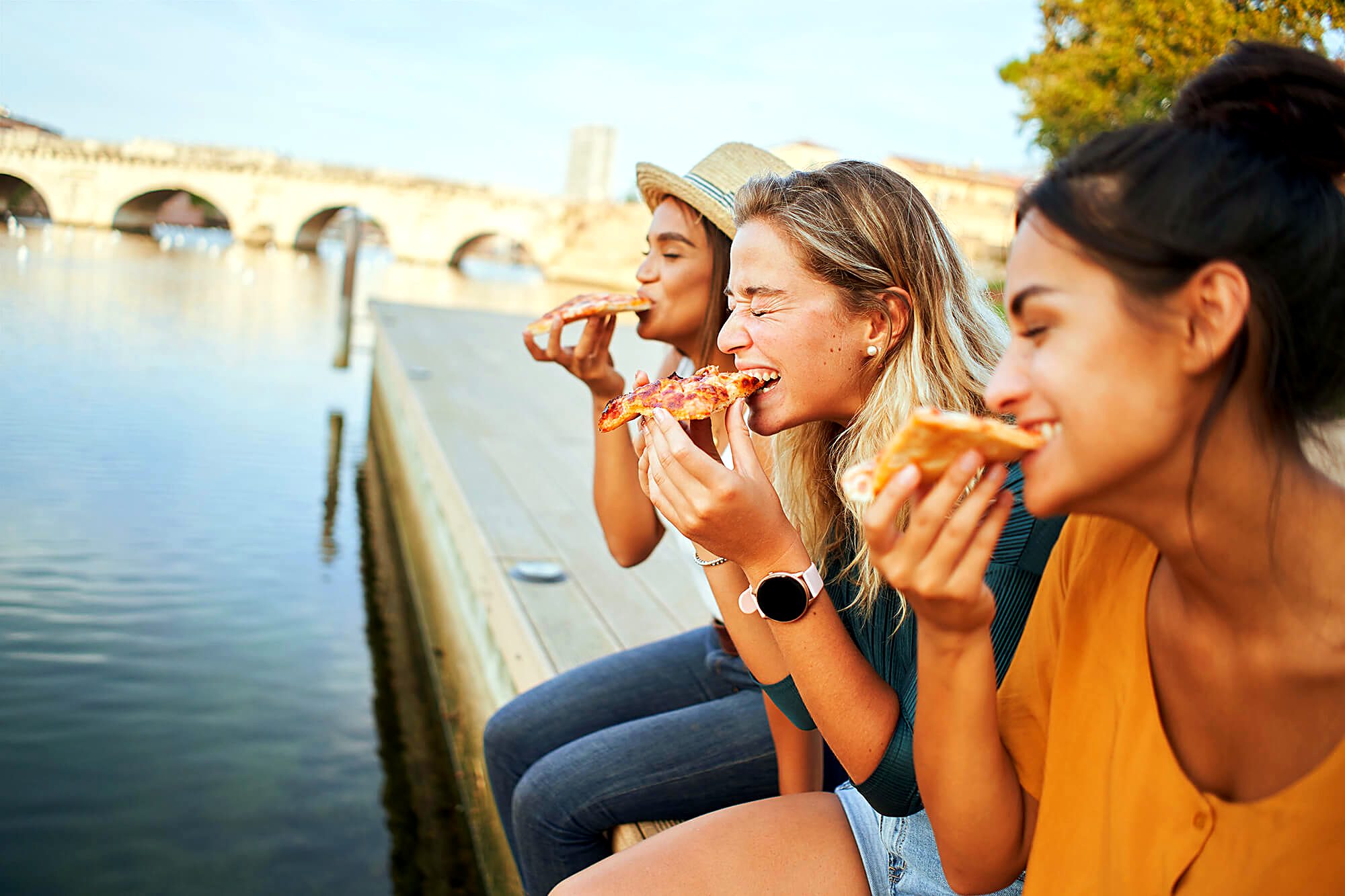 Students eating pizza by the river in Italy