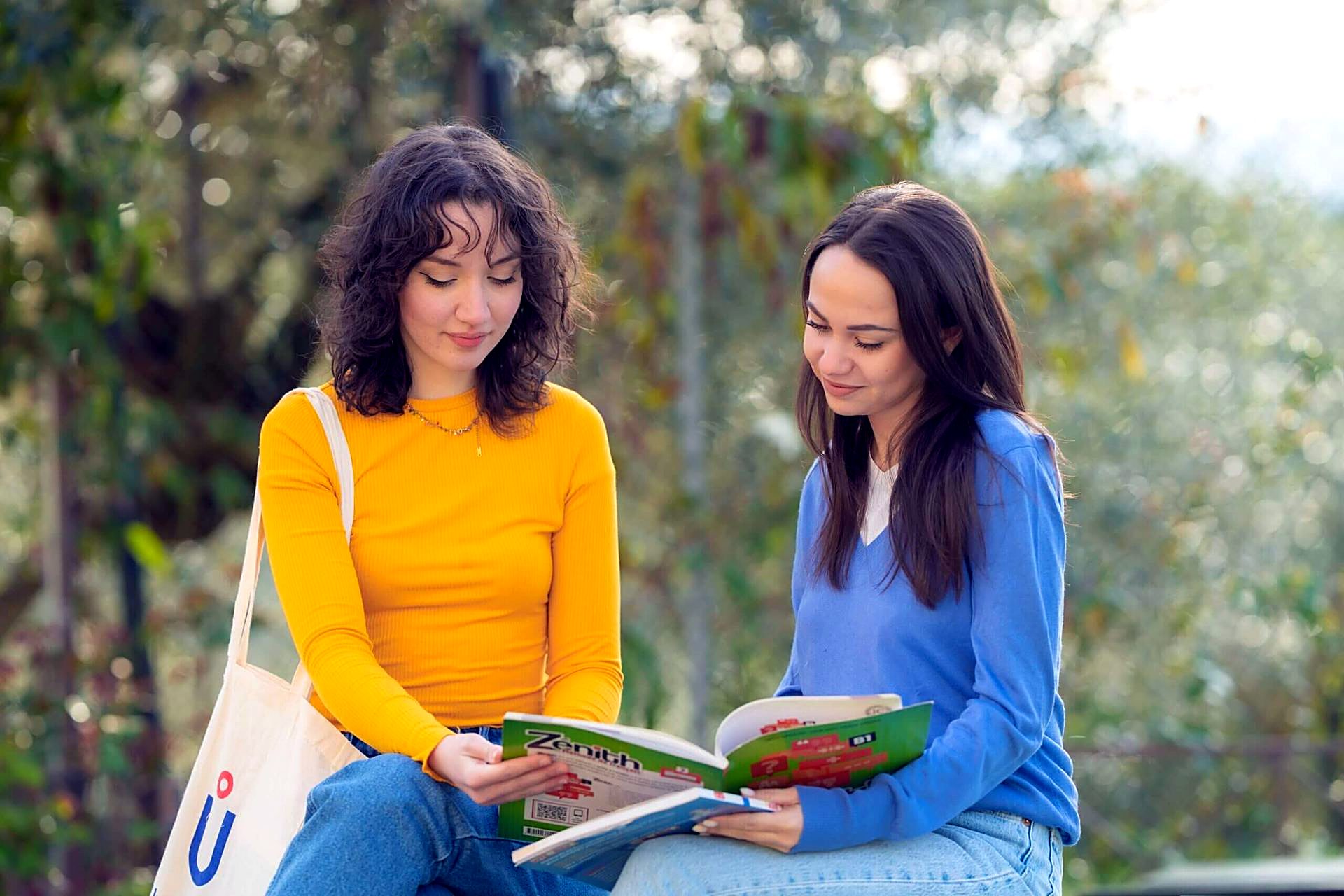 Two Unicollege students reading outdoors on campus