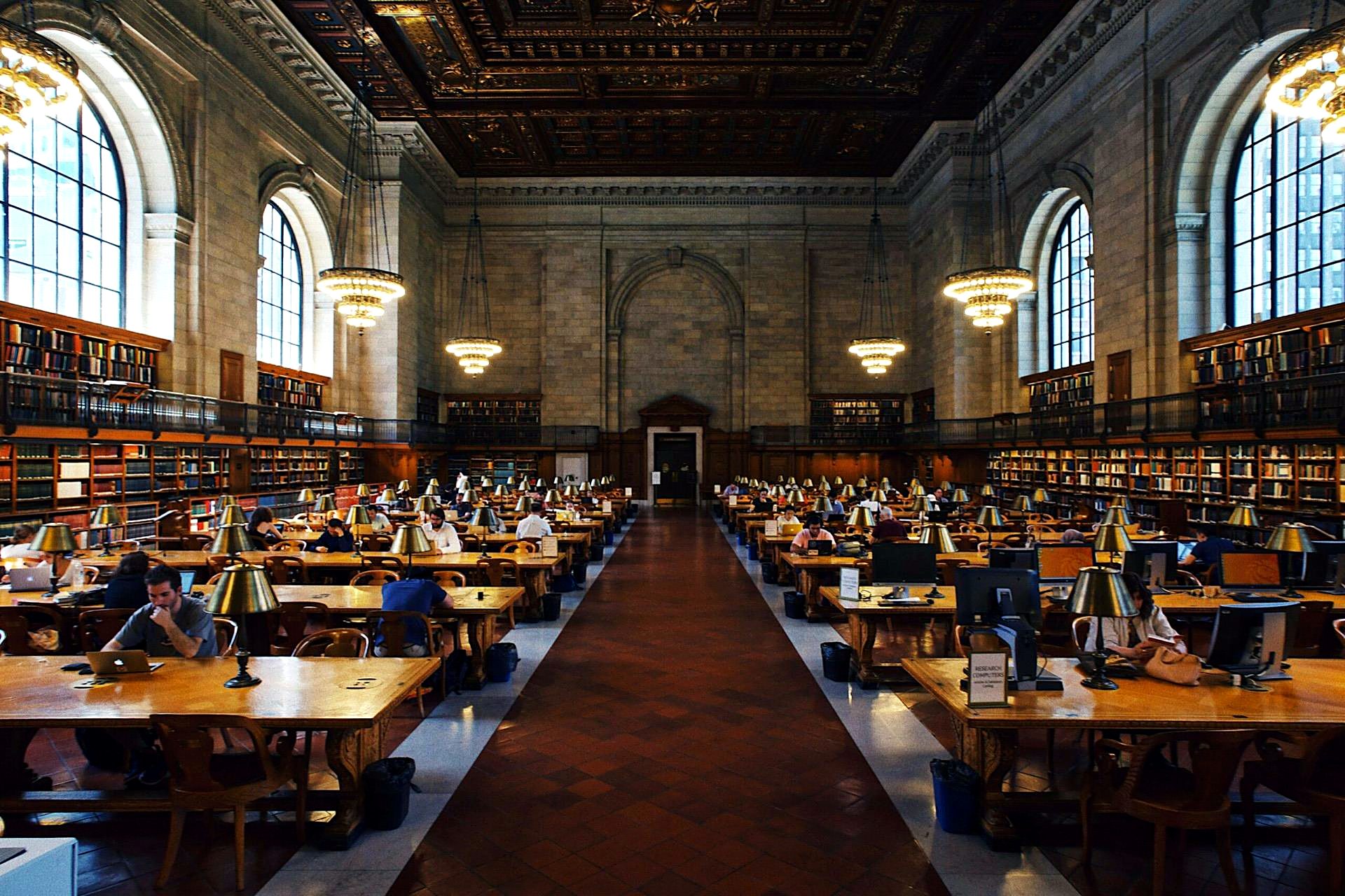 Students working in a monumental university library reading room